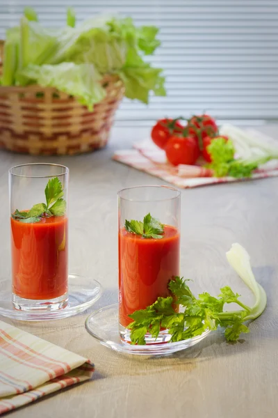 Dos vasos con el jugo de tomate, los tomates, los tallos y las hojas del apio a la mesa —  Fotos de Stock