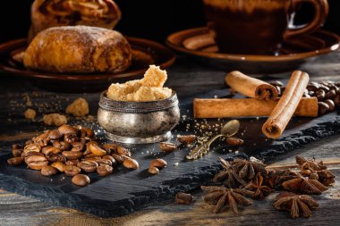 Kahverengi şeker, kahve taneleri ve tarçın kayrak siyah bir plaka üzerinde sopa