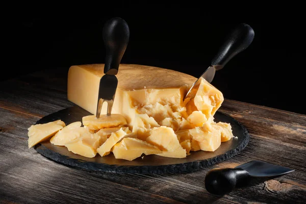 Parmesão de queijo com um conjunto de facas na tábua de ardósia redonda em estilo rústico Imagens De Bancos De Imagens
