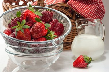 Bir kevgir ve süt krem bir sürahi içinde olgun taze çilek