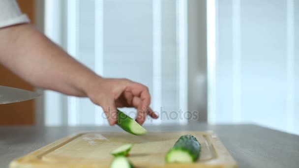 Handen van de grote keuken van cook mes een verse komkommer op een snijplank van een boom — Stockvideo