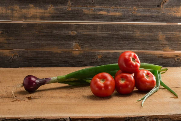 Zielone cebule i pomidory na tle starej płyty — Zdjęcie stockowe