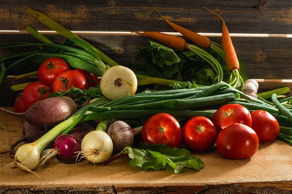 Cebollas verdes, ajo, zanahorias, remolacha y tomates sobre el fondo de viejas tablas grises —  Fotos de Stock