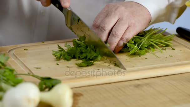 Handen van de grote keuken van cook mes een verse groene peterselie op een snijplank van een boom — Stockvideo
