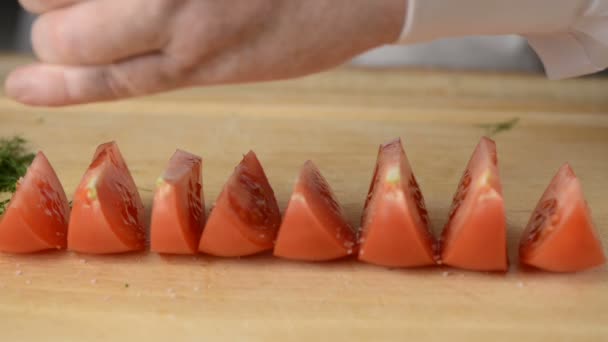 Der Mann salzt Scheiben des geschnittenen Tomatensalzes, bestreut gemahlenen Pfeffer und das zerkleinerte Fenchelgemüse — Stockvideo