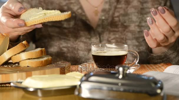 La mujer con la manicura hermosa tiene el café negro y come el bocadillo de la hogaza blanca con la mantequilla — Vídeos de Stock