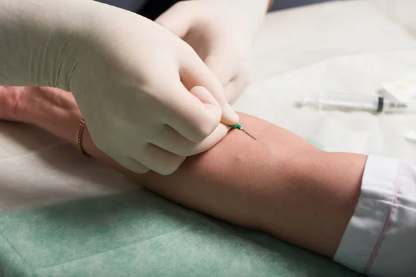 Mãos em látex luvas médicas realizar punção venosa na área de dobra ulnar da mão do paciente — Fotografia de Stock