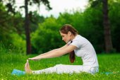 Schöne junge Frau macht Yoga-Übungen im Freien