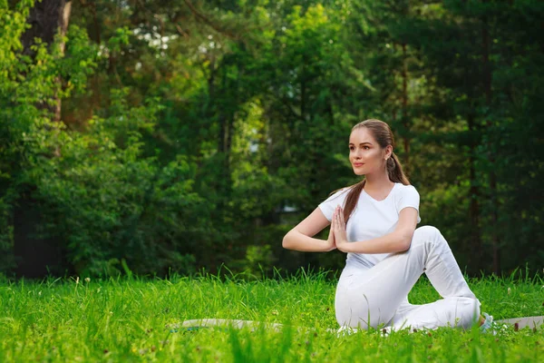 Güzel genç bayan dışarıda yoga yapıyor.