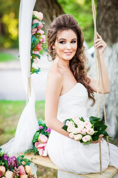 屋外でポーズの花を持つ美しい若い花嫁 — ストック写真