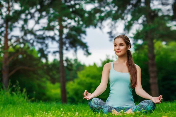 Güzel genç bayan dışarıda yoga yapıyor.