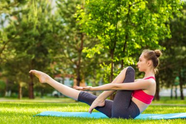 Güzel genç bayan dışarıda yoga yapıyor.
