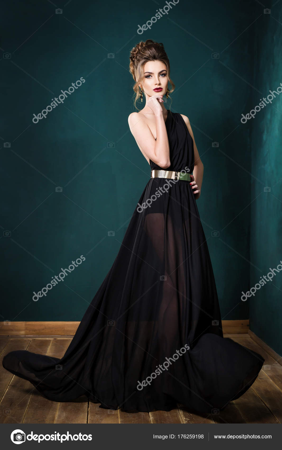 Nice woman with makeup and curly hairstyle in gold evening gown on black  background Stock Photo - Alamy