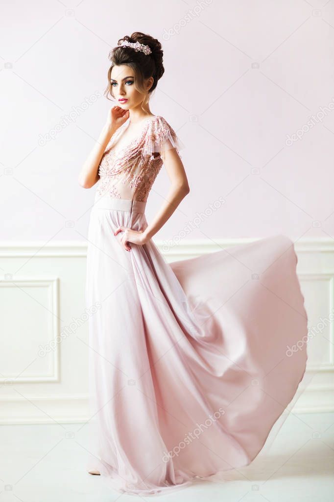 beautiful woman with hairstyle in elegant pink dress at vintage room 