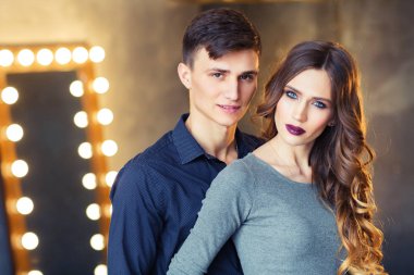 yakışıklı delikanlı ayna ve ışık ampuller ile odada duran onun güzel kadın sarılma