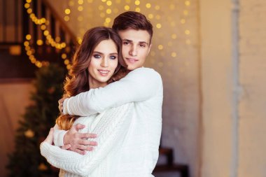 Noel ışıkları ile odada duran kız arkadaşı kucaklayan delikanlı