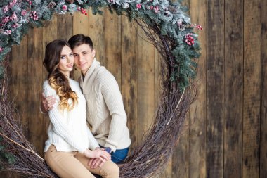 Dekoratif Noel çelenk üzerinde oturan mutlu genç Çift