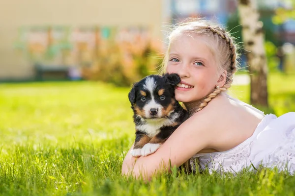 Blond Dziewczynka Gra Cute Puppy Czarny Siedząc Zielonej Trawie — Zdjęcie stockowe