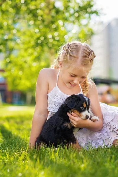 Blond Dziewczynka Gra Cute Puppy Czarny Siedząc Zielonej Trawie — Zdjęcie stockowe