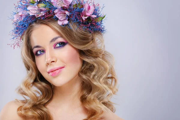 年轻美丽的妇女的肖像戴着粉红色和蓝色的花朵 在灰色背景的花圈 — 图库照片