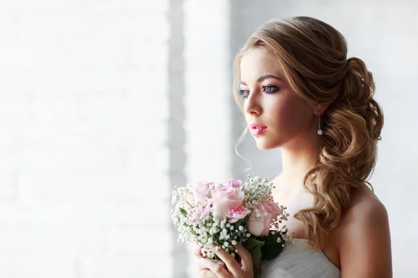 年轻美丽的女人在白色的婚纱礼服摆在粉红色玫瑰花束的时尚肖像 — 图库照片