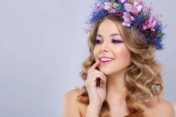年轻美丽的妇女的肖像戴着粉红色和蓝色的花朵 在灰色背景的花圈 — 图库照片