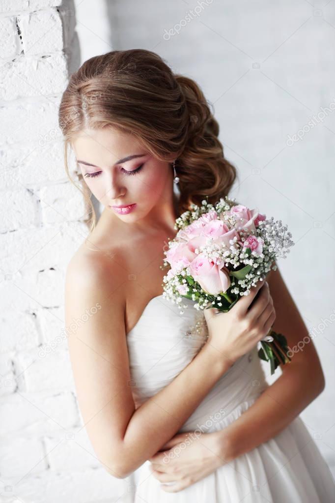 fashion portrait of young beautiful woman in white wedding dress posing with bouquet of roses