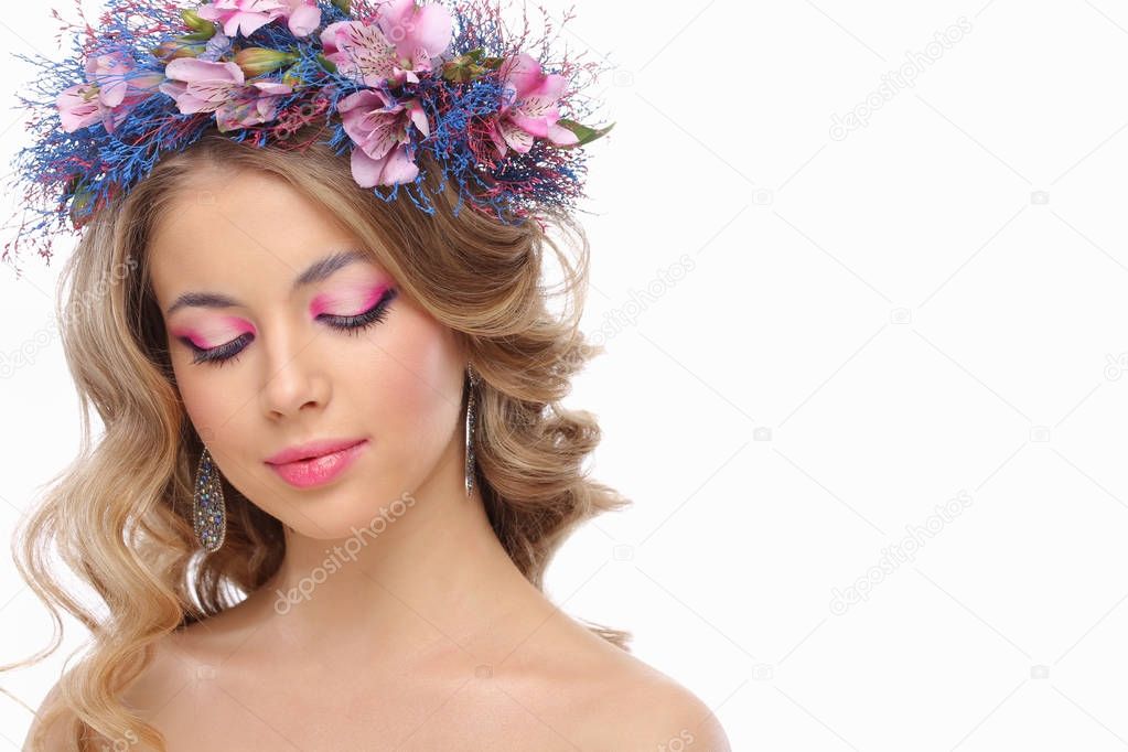 portrait of young beautiful woman wearing wreath of pink and blue flowers posing isolated over white background 