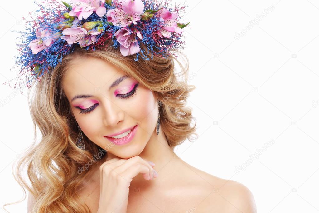 portrait of young beautiful woman wearing wreath of pink and blue flowers posing isolated over white background 