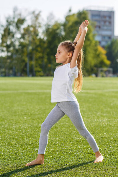 Маленькая девочка делает фитнес на открытом воздухе
