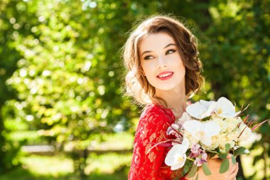 Buket tutan zarif kırmızı dantelli elbiseli güzel genç kadın 