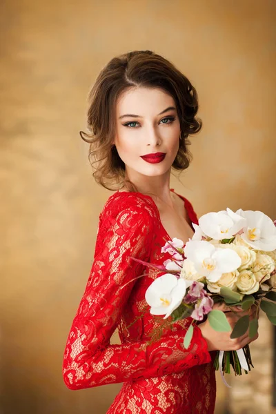 花束を持ってエレガントな赤いレースのドレスでゴージャスな若い女性 — ストック写真