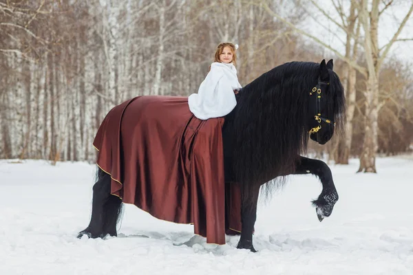 Petite fille monte un cheval friesian, en plein air — Photo