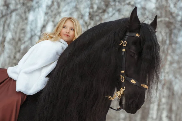 Little blonde girl riding a friesean horse — Stock Photo, Image