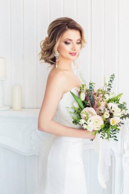 Güzel genç kadın beyaz düğün elbise ile buket 
