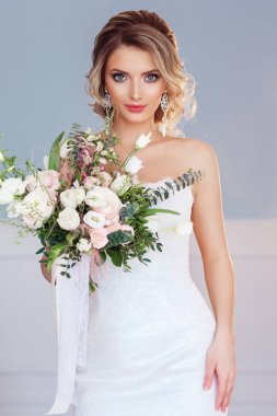 Güzel genç kadın beyaz düğün elbise ile buket 