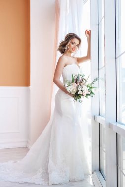 Güzel genç kadın beyaz düğün elbise ile buket 