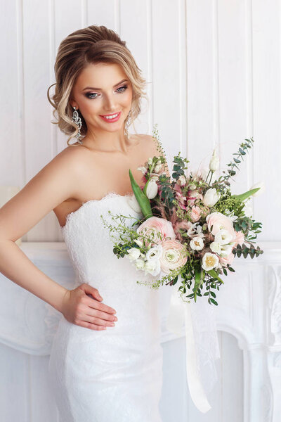 Gorgeous young woman in white wedding dress with bouquet 