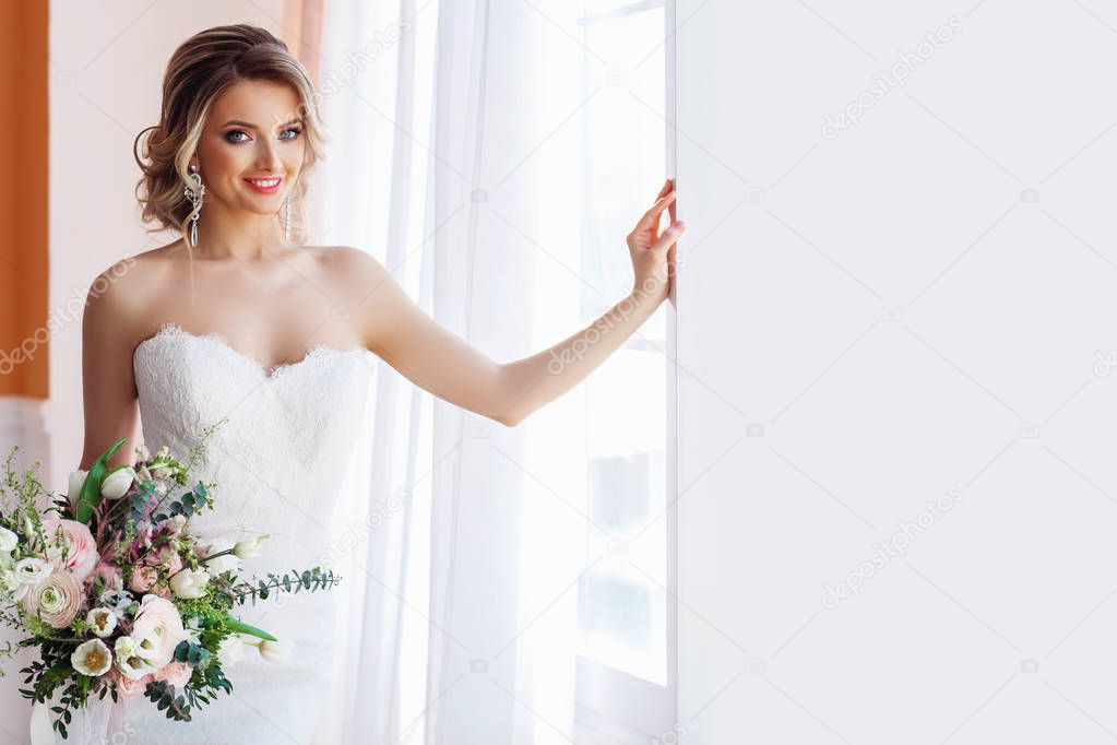 Gorgeous young woman in white wedding dress with bouquet 