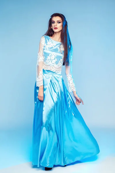 Piękna Kobieta Stwarzających Niebieskiej Sukience Stojąc Niebieskim Tle — Zdjęcie stockowe