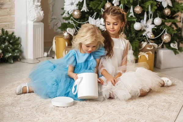 两个漂亮女孩在圣诞树旁开礼物 — 图库照片