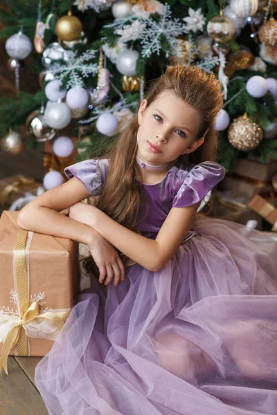 Bir Noel hediyesi ile Lila elbiseli küçük şirin kız 