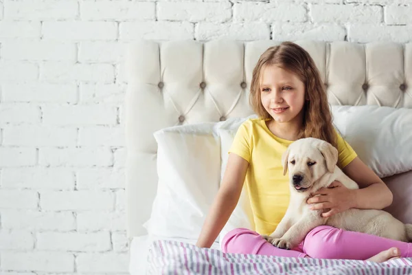 美丽的小女孩与金黄猎犬狗在床上 — 图库照片