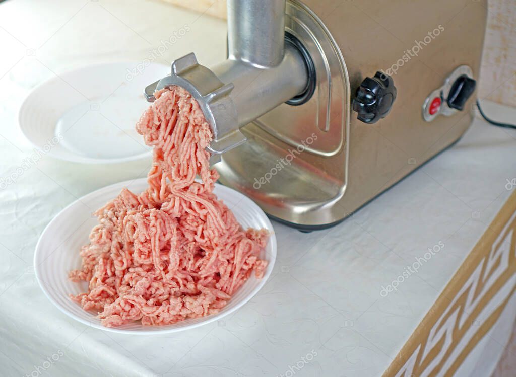 A meat grinder grinds meat. Processing meat into minced meat using a meat grinder.