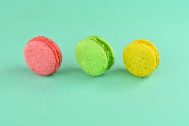 Turkuaz arka planda makarna. Renkli arka planda çok renkli badem kurabiyeleri. Tatlı olarak turkuaz arka planda çok renkli kurabiyeler..