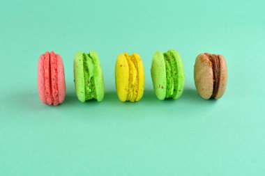 Turkuaz arka planda makarna. Renkli arka planda çok renkli badem kurabiyeleri. Tatlı olarak turkuaz arka planda çok renkli kurabiyeler..