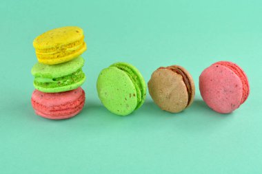 Turkuaz arka planda makarna. Renkli arka planda çok renkli badem kurabiyeleri. Tatlı olarak turkuaz arka planda çok renkli kurabiyeler..