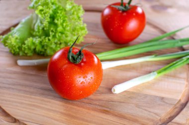 Ahşap zemin üzerinde salata ve soğan ile sulu kırmızı domatesler. Vejetaryen yemeği. Olgun domatesler, bir damla suyla..