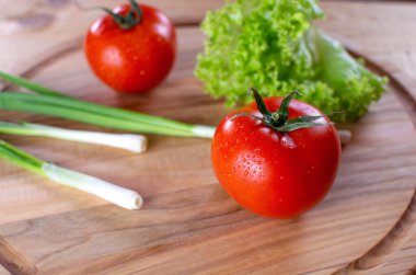 Ahşap zemin üzerinde salata ve soğan ile sulu kırmızı domatesler. Vejetaryen yemeği. Olgun domatesler, bir damla suyla..