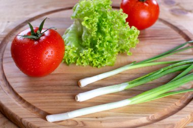 Ahşap zemin üzerinde salata ve soğan ile sulu kırmızı domatesler. Vejetaryen yemeği. Olgun domatesler, bir damla suyla..